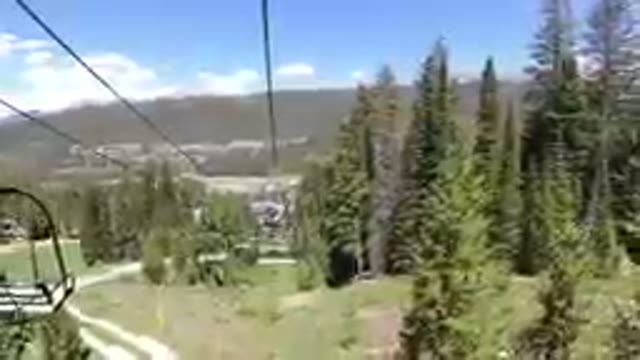 View Of A Ski Lift Going Up A Hill With A Town In The Distance