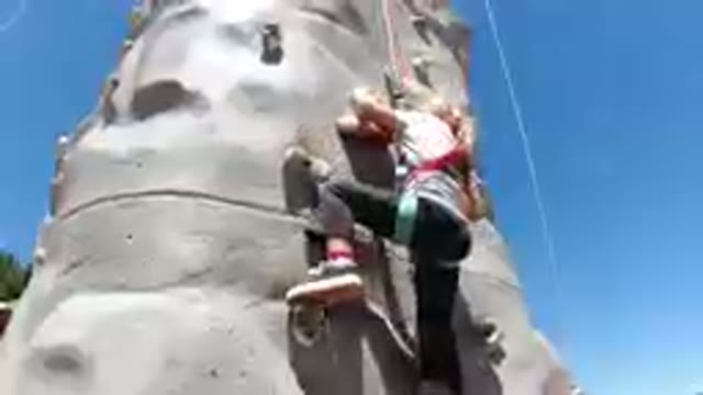 Girl Climbing On A Rock Wall With A Rope