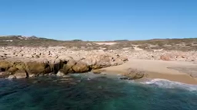 LAGUNA BEACH LOS CABOS BCS MEXICO-2023: Small Boat On Water Near Rocky Shoreline