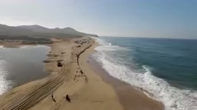 MIGRINO BCS MEXICO-2023: On The Beach With A Long Line Of Vehicles