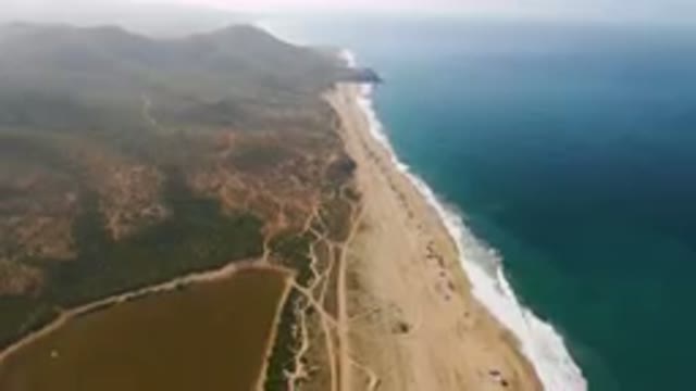MIGRINO BCS MEXICO-2023: Aerial Beach And A Body Of Water With Mountains In The