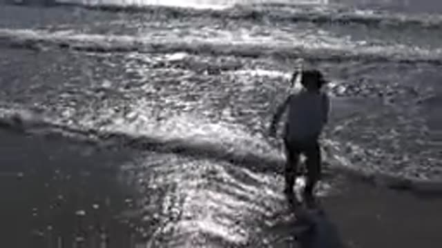 MALIBU CALIFORNIA-2020: Young Girl Jumps Waves On The Ocean At Sunset