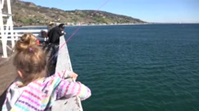 MALIBU CALIFORNIA-2020: Girl Wearing White Striped Jacket Looks at Blue Ocean