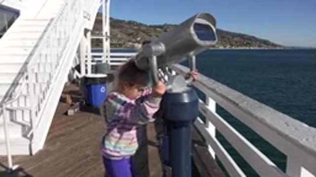 MALIBU CALIFORNIA-2020: Young Girl Playing With Binoculars On Seaside Pier