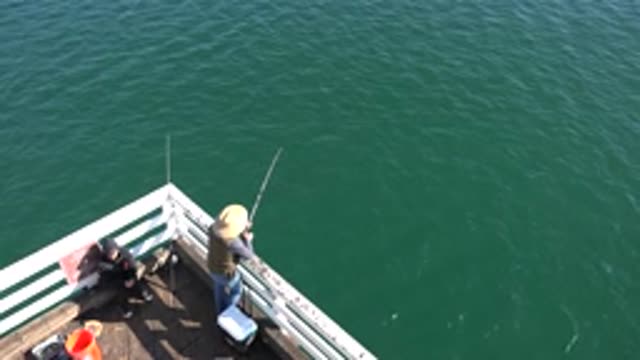 MALIBU CALIFORNIA-2020: Two People Fishing Off A Pier High Above Body Of Water