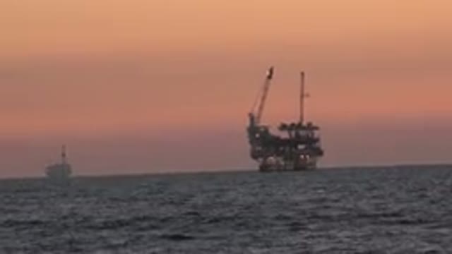 HUNTINGTON BEACH CALIFORNIA-2020: Distant View Of An Oil Factory In The Ocean At Sunset