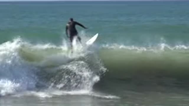 HUNTINGTON BEACH CALIFORNIA-2020: Person On Surfboard Rides Up Over The Crest Of Wave