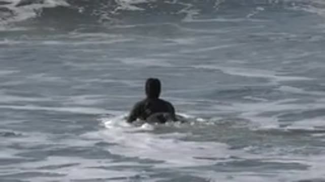 HUNTINGTON BEACH CALIFORNIA-2020: Man in Black Swimsuit Tries to Swim
