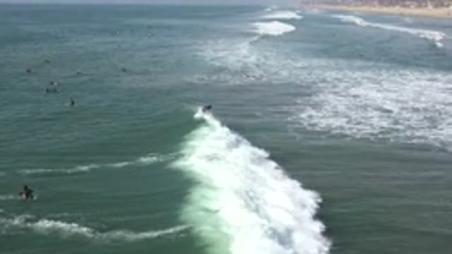 HUNTINGTON BEACH CALIFORNIA-2020: Dozens Of Surfers Watch A Surfer On A Small Wave