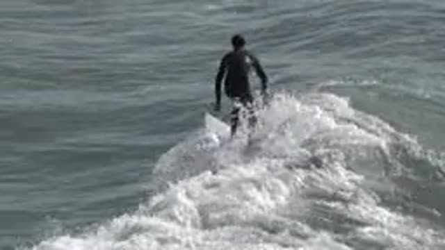 HUNTINGTON BEACH CALIFORNIA-2020: Surfer Wearing Wetsuit Stands On Board While