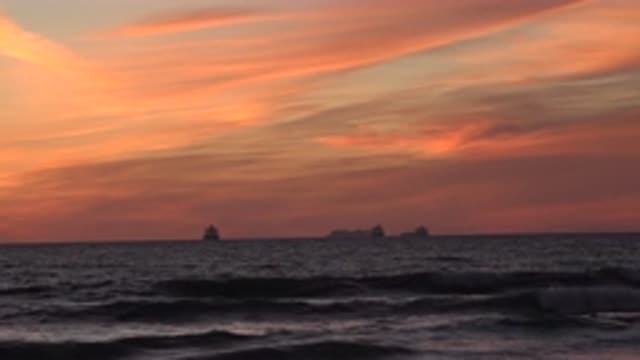 HUNTINGTON BEACH CALIFORNIA-2020: Waves Rolling In On A Beach While Three Ships