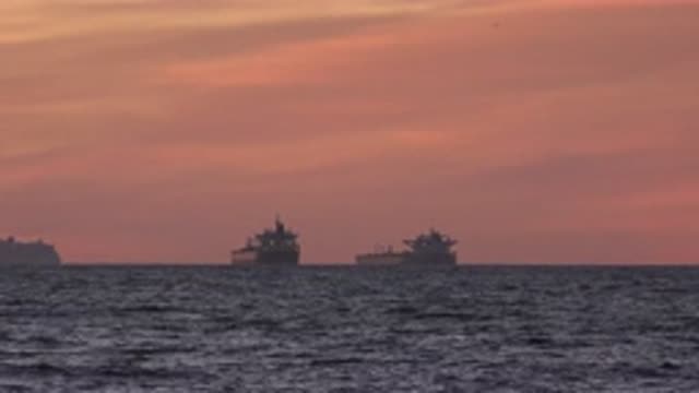 HUNTINGTON BEACH CALIFORNIA-2020: Two Barges Floating Offshore at Sunset
