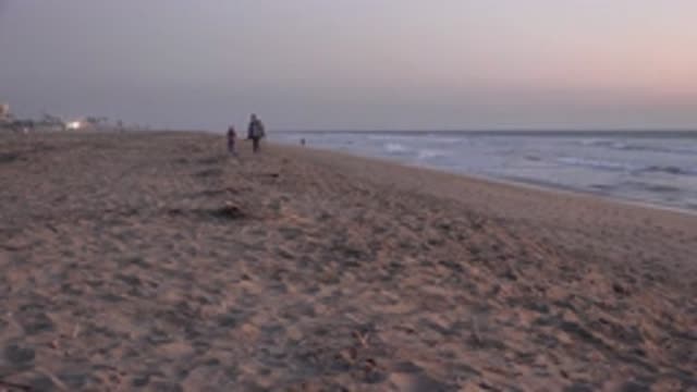 HUNTINGTON BEACH CALIFORNIA-2020: People Strolling on the Beach Near the Waves
