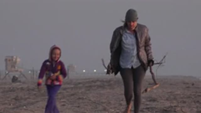 HUNTINGTON BEACH CALIFORNIA-2020: Mother Carrying Logs Walking Along the Shore