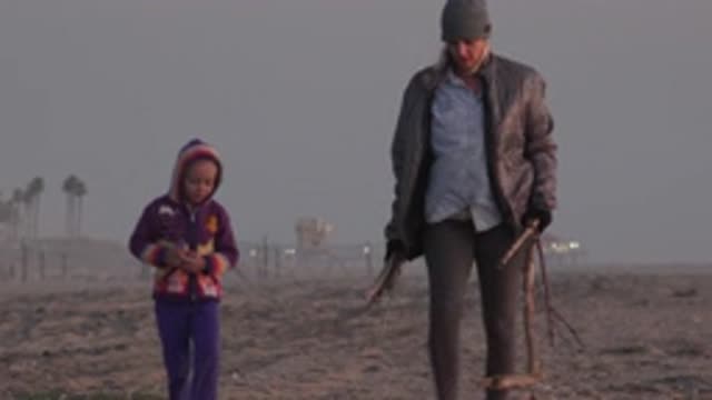 HUNTINGTON BEACH CALIFORNIA-2020: Young Girl And Woman Carrying Branches Walk