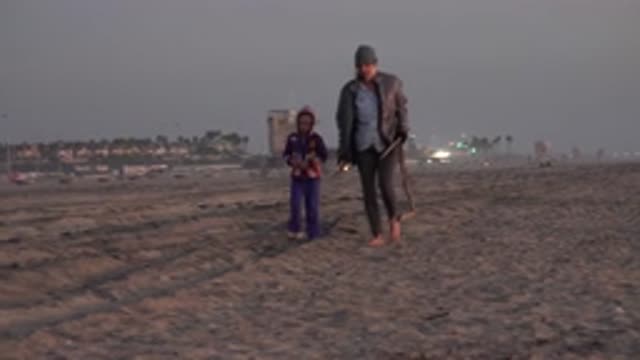HUNTINGTON BEACH CALIFORNIA-2020: Woman And Girl Walk Along Beach Talking And Collecting Sticks