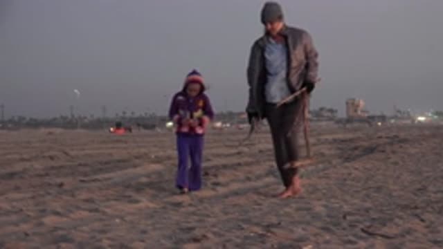 HUNTINGTON BEACH CALIFORNIA-2020: Woman Wearing Tan Jacket Walks With Girl