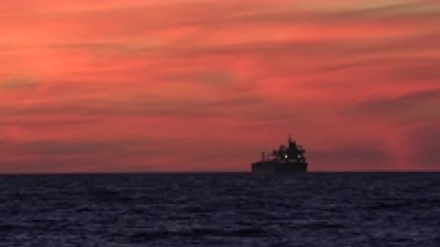HUNTINGTON BEACH CALIFORNIA-2020: A Large Ship Floats On The Ocean At Dusk Under