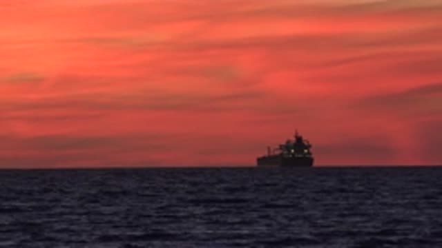 HUNTINGTON BEACH CALIFORNIA-2020: Sunset At Sea With Shipping Ship And Beautiful Waves