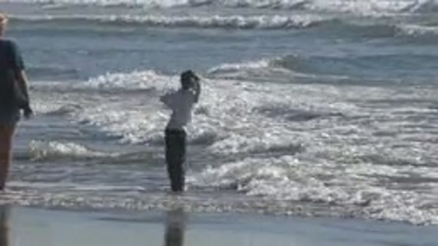 Child Playing In Ocean Waves With Adult