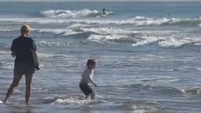 HUNTINGTON BEACH CALIFORNIA-2020: Girl Wearing White Shirt Jumps In Ocean Water