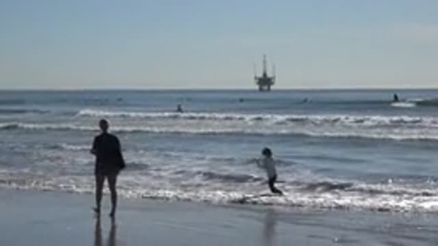 HUNTINGTON BEACH CALIFORNIA-2020: Child Jumping Happily On The Beach Dipping His Feet