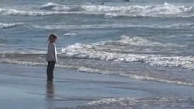HUNTINGTON BEACH CALIFORNIA-2020: Girl Wearing White Shirt Stands On Beach