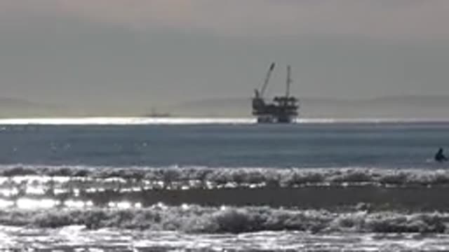 HUNTINGTON BEACH CALIFORNIA-2020: A View Of A Towering Oil Rig And Waves