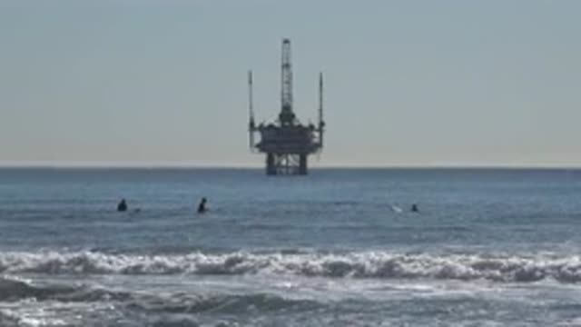 HUNTINGTON BEACH CALIFORNIA-2020: View Of Surfers And Offshore Oil Rig On A Sunny Day