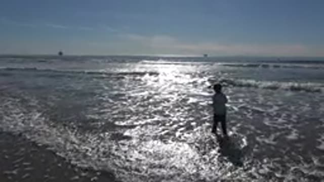 HUNTINGTON BEACH CALIFORNIA-2020: A Little Girl Happily Plays and Jumps the Waves