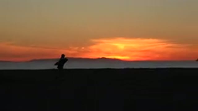 HUNTINGTON BEACH CALIFORNIA-2020: A Couple Wearing Backpacks Walking On A Beach