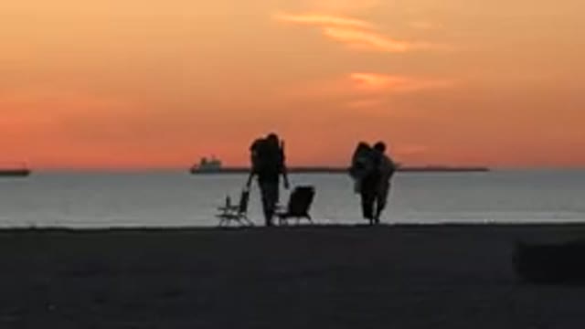 HUNTINGTON BEACH CALIFORNIA-2020: Two White Adults Carry Beach Chairs And Packs