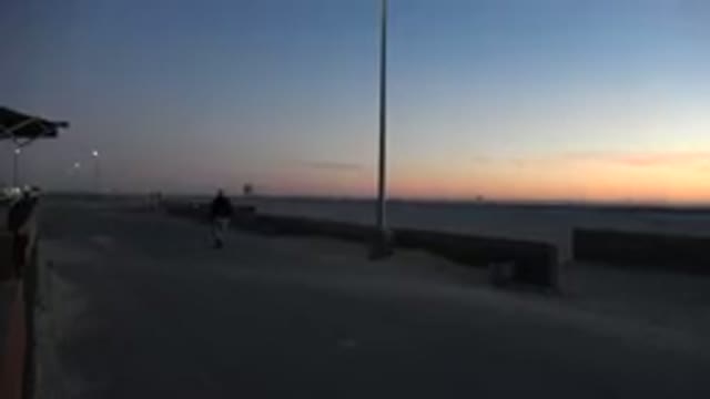 HUNTINGTON BEACH CALIFORNIA-2020: Man in Dark Suit and Light Colored Pants Walking Beach at Dusk