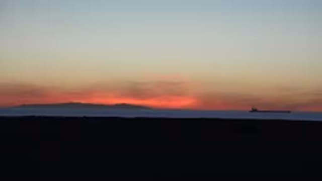 HUNTINGTON BEACH CALIFORNIA-2020: Solo Bird Flying Low Over Blue Ocean At Sunset