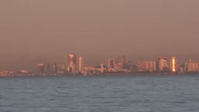 HUNTINGTON BEACH CALIFORNIA-2020: Birds Flying Above The Sea With Buildings At