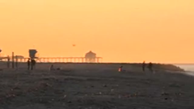 HUNTINGTON BEACH CALIFORNIA-2020: A Flock Of Birds Fly Over The Beach At Dusk