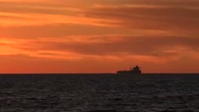 HUNTINGTON BEACH CALIFORNIA-2020: View Of Black Boat Silhouette In Water Against Golden Sunset