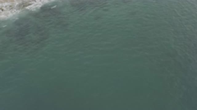 EAST CAPE BCS MEXICO-2019: Aerial View Of Small Waves Crashing Against Grey Rocks