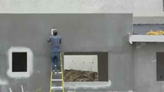 CABO SAN LUCAS MEXICO-2020: Man Works Hard As He Paints Grey Wall While Standing
