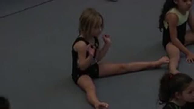 CABO SAN LUCAS MEXICO-2020: A Little Girl Wearing Gym Clothes Sits On A Mat And Stretches