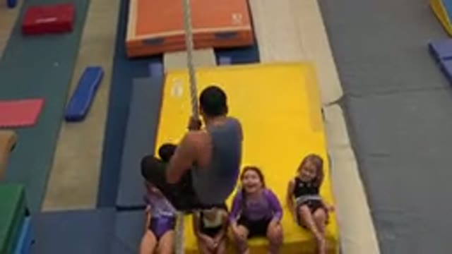 CABO SAN LUCAS MEXICO-2020: Man Wearing Grey T-Shirt Climbs Down Tan Rope In Gymnasium