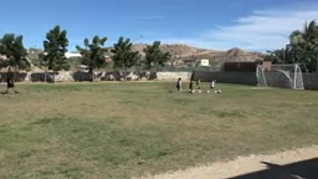 LOS CABOS MEXICO-2019: Six Children Playing Football Under The Clear Sky Of