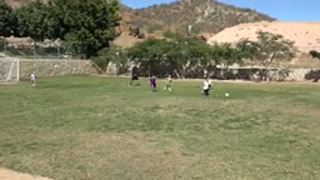 LOS CABOS MEXICO-2019: Children Play Soccer In A Grassy Field Enclosed By A Rock Wall