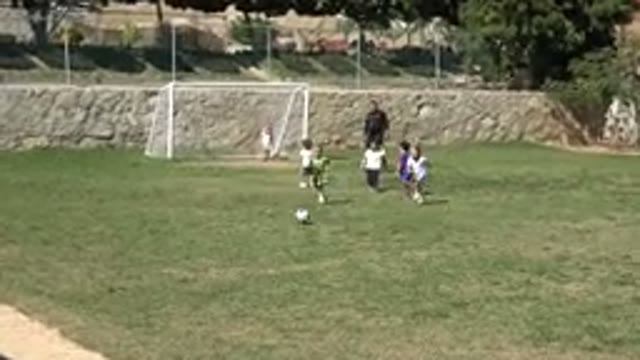 LOS CABOS MEXICO-2019: Boy Wearing Green Shirt With White Shoes Runs After Black Soccer Ball