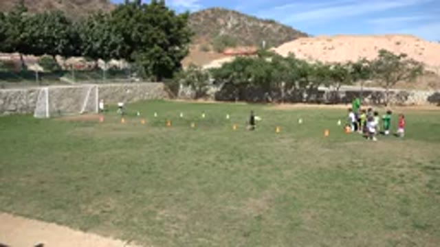 LOS CABOS MEXICO-2019: Small Children Run Drills On A Soccer Field While A Coach