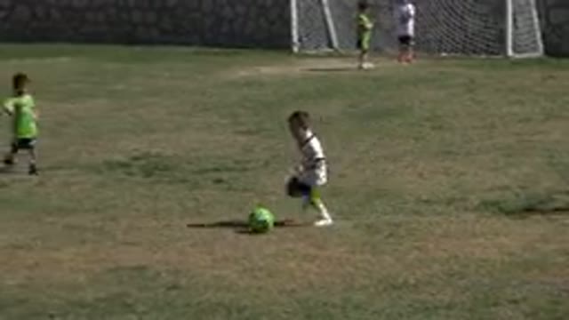 LOS CABOS MEXICO-2019: A Small Boy Kicks A Soccer Ball Up A Grassy Field Past