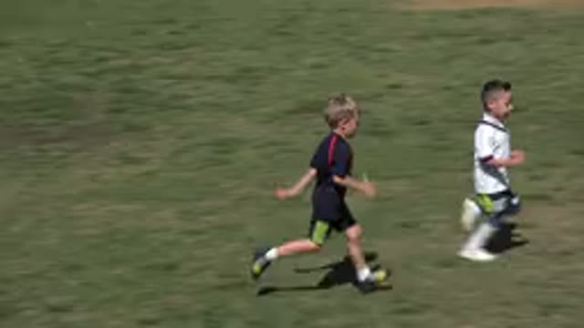 LOS CABOS MEXICO-2019: Children In Football Gear Run Across Grass Chasing A Ball