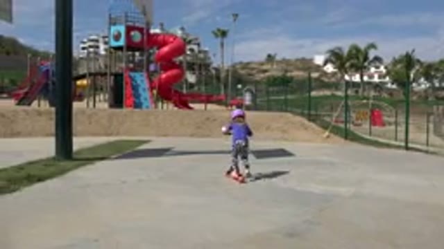 LOS CABOS MEXICO-2019: Little Girl Wearing Purple Shirt and Helmet Rides Scooter