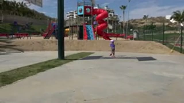 LOS CABOS MEXICO-2019: Child Bike Riding Near Playground Adult Cleaning Trash