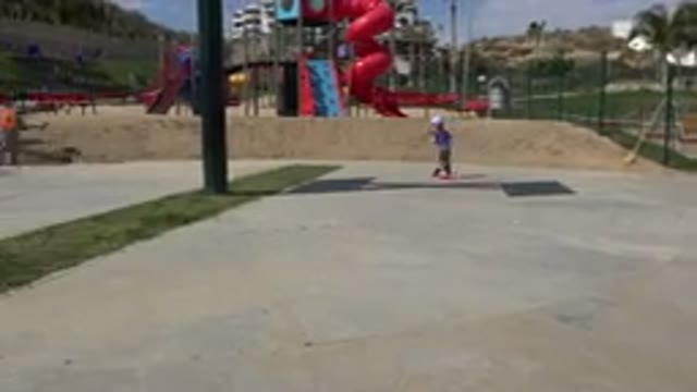 LOS CABOS MEXICO-2019: Child On Scooter At Playground While Worker Shoves Dirt